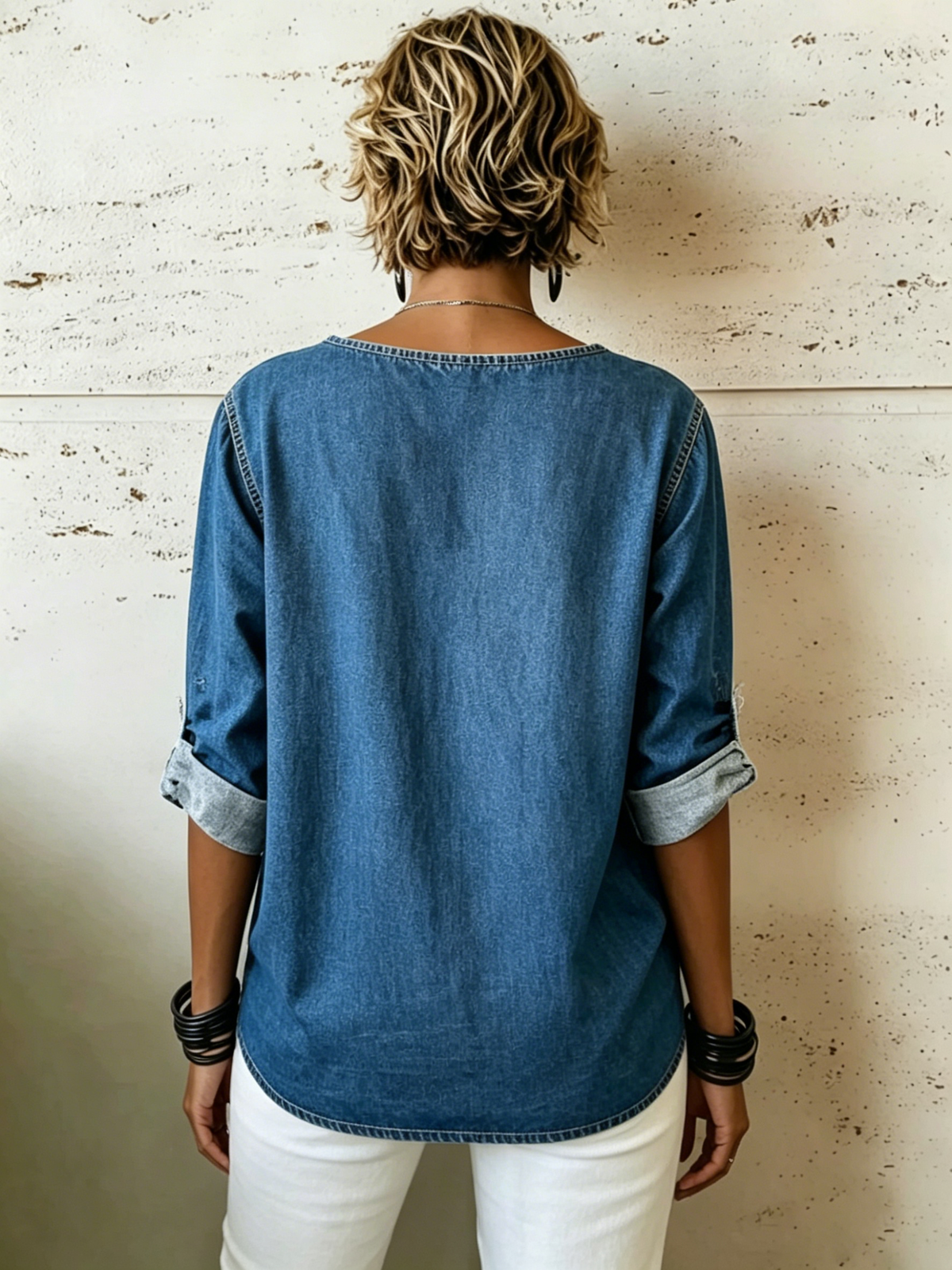 Camisa de mezclilla suave con ajuste relajado y efecto desgastado, con cuello redondo, mangas remangadas, hebillas metálicas laterales, aberturas en los costados y dobladillo asimétrico.