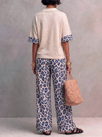 Dames tweedelig set met een casual, losvallend, kort mouwig pullover topje met kraag en een hoge taille, losvallende, wijde broek met luipaardprint.
